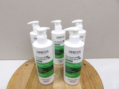 trois flacons de gel hydroalcoolique Dercos posés sur un plateau en bois