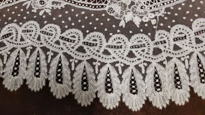 un gros plan sur une dentelle blanche posée sur un morceau de tissu