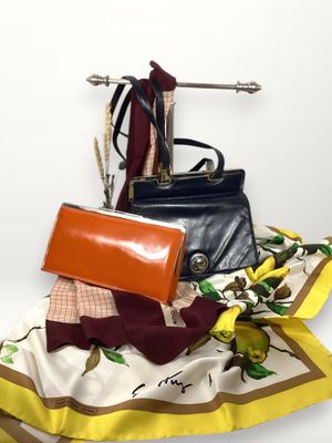 un sac à main noir et une écharpe jaune posés sur une surface blanche