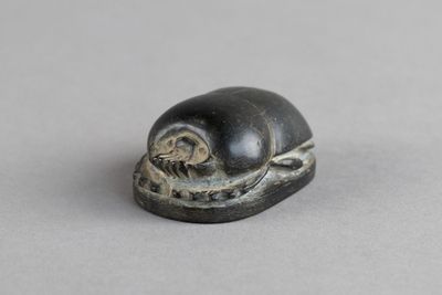 un gros plan d'une figurine représentant un escargot posée sur une surface grise