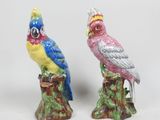 deux figurines représentant des oiseaux colorés perchés sur une souche d'arbre
