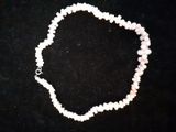 un gros plan d'un collier de perles blanches posé sur une surface noire