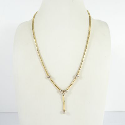 a gold necklace with a cross pendant and a chain on a mannequin