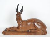 statue of an antelope laying down on a white surface