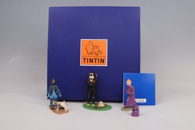 three figurines of people standing in front of a blue box