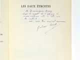 un livre ouvert, dont une page est écrite à la main, posé sur une table