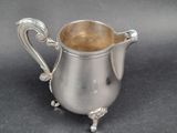 a silver pitcher with a handle on a table