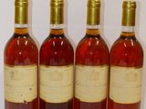four bottles of wine are lined up on a white surface