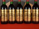 four bottles of wine are lined up on a red cloth