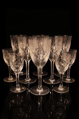 seven crystal wine glasses are lined up in a row on a black surface