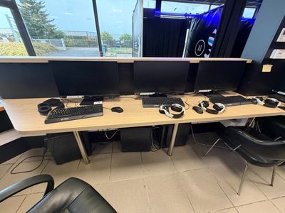a desk with two monitors and a keyboard in front of a window