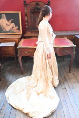 une femme debout dans une pièce, vêtue d'une robe