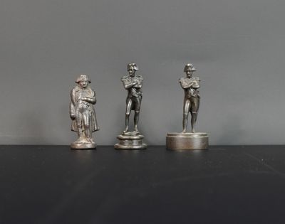 trois figurines en argent représentant un homme et une femme, posées sur des socles