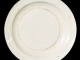 an old white plate with a brown rim on a black background