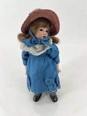 une poupée qui porte une robe bleue et un chapeau