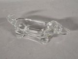 a glass dog shaped dish with a handle on a table