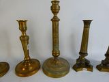 several brass candlesticks are lined up on a white surface