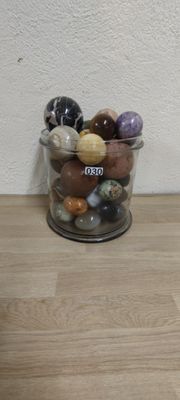 a glass jar filled with different colored rocks on a wooden table