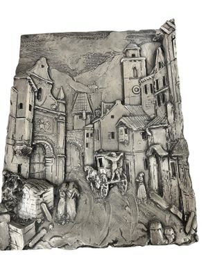 a silver plate with a picture of a town on it
