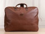 a brown leather briefcase sitting on top of a wooden table
