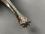 a close up of a silver spoon with a flower on it