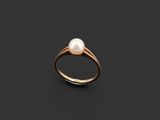 a pearl and gold ring on a black background