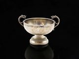 une coupe ancienne en argent, ornée d'une poignée en forme de dragon sur un fond noir