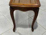 une petite table en bois avec un plateau en osier, posée sur un sol carrelé