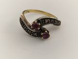 a close up of a ring with two stones on a white surface