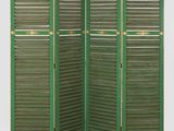 un paravent vert dont les volets sont ouverts sur un fond blanc