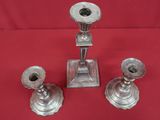 trois bougeoirs en argent posés sur une nappe rouge, sur une table