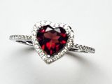 une photo d'une bague ornée d'une pierre de grenat en forme de cœur, avec un anneau serti de diamants