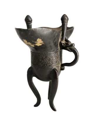un vase noir et doré muni d'une anse, sur fond blanc