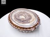 a picture of a silver and gold broochle on a white plate