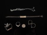 des bijoux en argent sur fond noir, comprenant une chaîne, un bracelet, une bague et d'autres articles