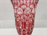 un vase en verre rouge posé sur une étagère transparente