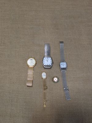trois montres et un bracelet sont posés sur une surface marron