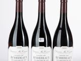 trois bouteilles de vin sont alignées sur une surface blanche