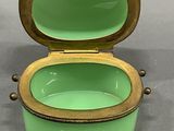 a green and gold box with a lid on a gray surface