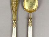 two spoons and a knife on a table with a gray background