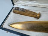 a gold colored knife in a case on a white table