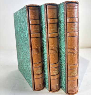 three books are lined up in a row on a white surface