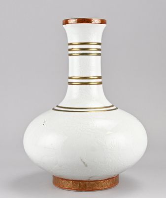 un vase blanc et doré, bordé d'or, posé sur un socle