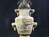 une photo d'un vase posé sur un socle, sur fond noir