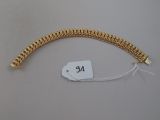 a close up of a gold bracelet with a tag on it