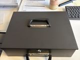 une boîte noire posée sur un bureau, à côté d'un écran d'ordinateur