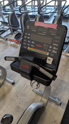 many tread machines in the gym with a laptop on one of them