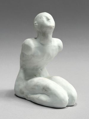 sculpture of a woman sitting on her knees on a gray surface