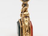 a close up of a gold charm with a black and red bead