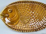 a gold fish shaped dish with a spoon on the side